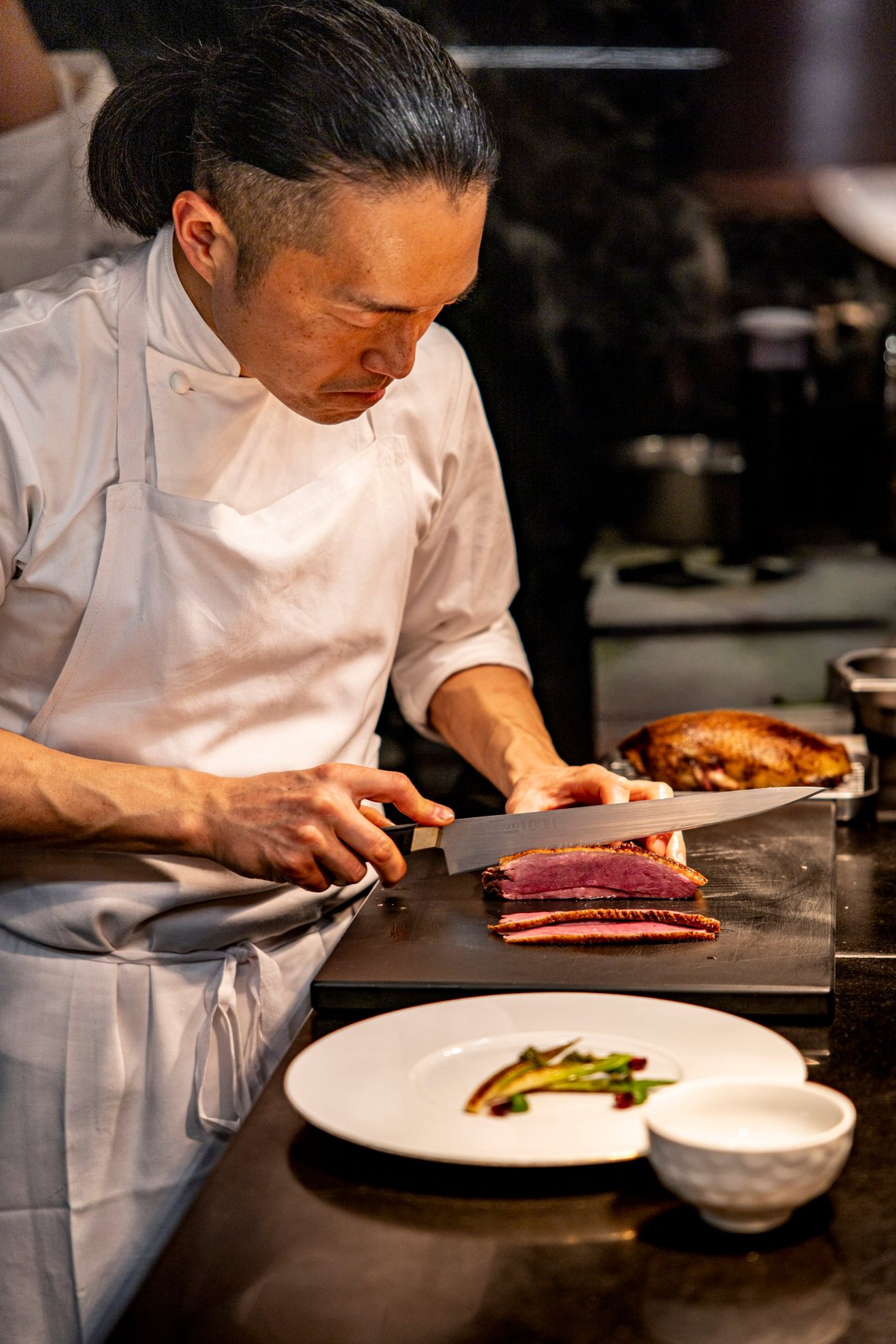 Le chef Yoshitaka Takayanagi tranche la canette, à la cuisine de Granite